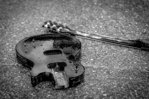 Broken guitar on the street in the rain.